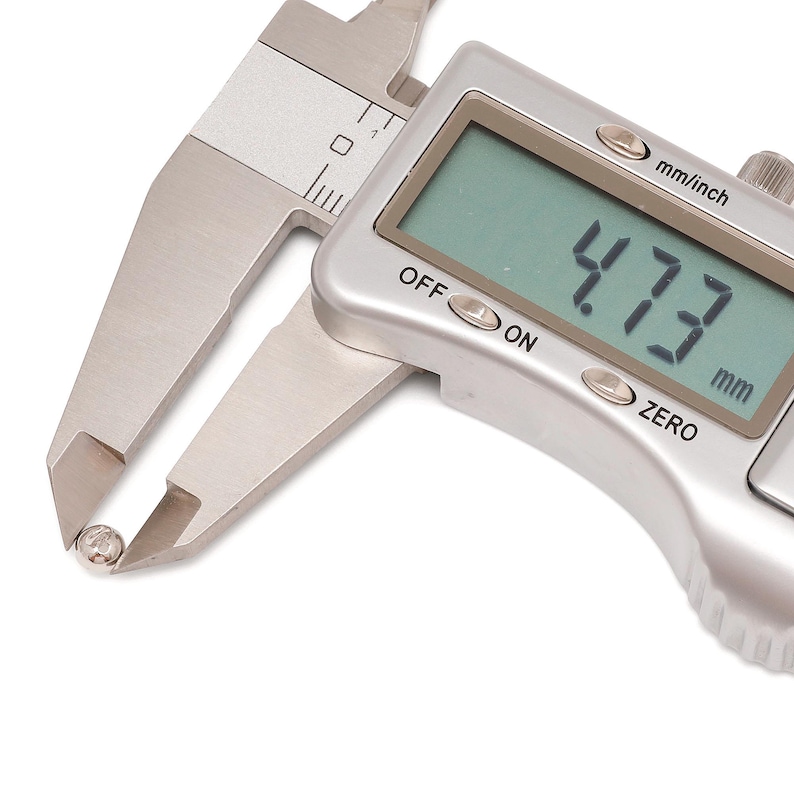 May include: A digital caliper measuring a small, round object. The digital display shows a measurement of 4.73 mm. The caliper is silver and has mm/inch and zero settings.