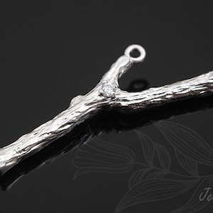 May include: Silver Y-shaped connector with a textured bark-like finish and a single clear rhinestone. The connector has two loops at the ends.