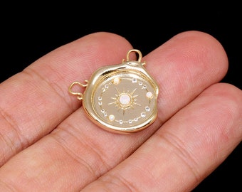 May include: Gold-toned pendant with a circular design featuring a starburst with a white opal center and small white pearls around the edge. The pendant has two loops for attaching a chain.