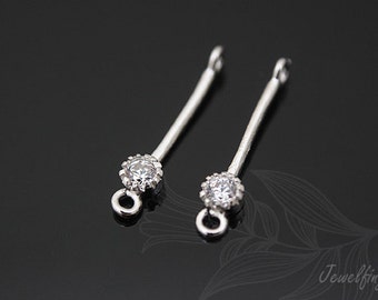 May include: Two silver earring findings with a clear rhinestone at the top and a small loop at the bottom.