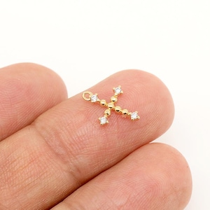 May include: A gold cross charm with small clear cubic zirconia stones.