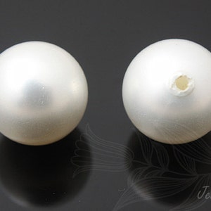 May include: Two white round pearl beads with a hole in the center for stringing.