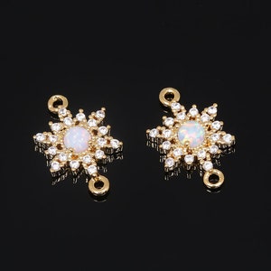 May include: Two gold-tone starburst connector charms with clear opal stones in the center. Each charm has two jump rings for attaching to jewelry.