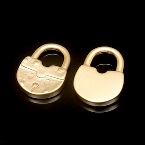 May include: Two gold-colored padlocks, one with a detailed design and the other smooth, on a black background.