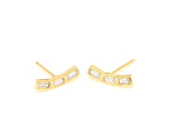 May include: A pair of gold earrings with a curved design featuring five clear rectangular stones.