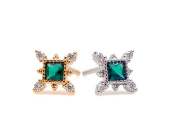 May include: Two stud earrings, one in gold tone and one in silver tone, each featuring a square-cut emerald green center stone surrounded by four small, round, clear accent stones set in a decorative, star-shaped metal frame with post backs.