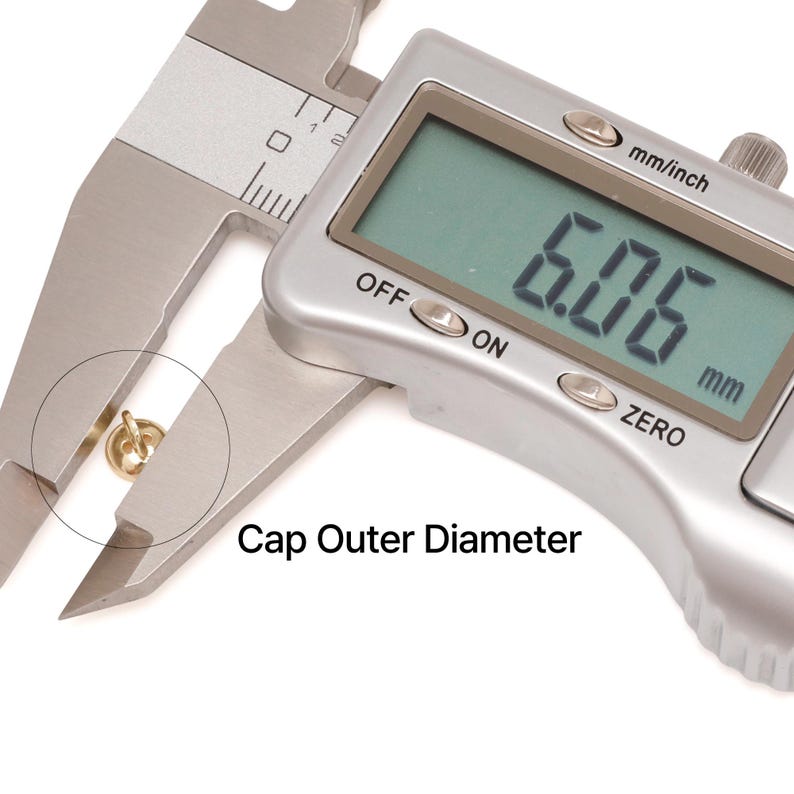 May include: A digital caliper measuring a small gold-coloured cap. The digital display shows 6.06 mm. The text "Cap Outer Diameter" is printed below the cap. The caliper is silver and the background is white.