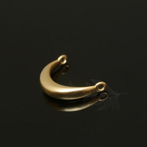 May include: A gold-colored metal crescent moon charm with two small loops at the ends.