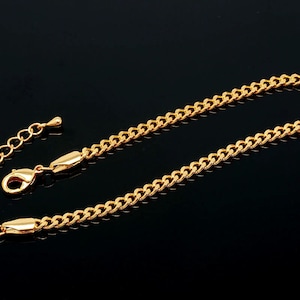 May include: A gold chain bracelet with a lobster clasp closure. The chain is a curb style with a shiny finish.
