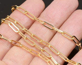 May include: A gold chain necklace with a delicate, flat, oval link design. The chain is shown draped over a hand.