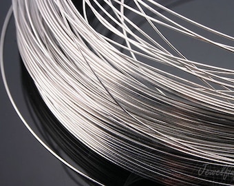 May include: A close-up of a spool of silver-coloured wire. The wire is tightly wound and has a smooth, shiny finish.