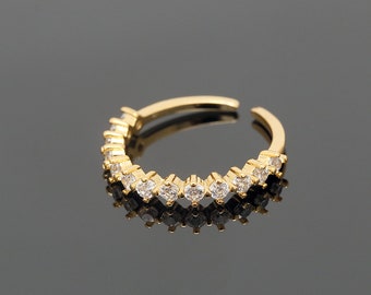 May include: A gold ring with a row of clear cubic zirconia stones set in a curved design.