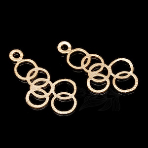 May include: Two gold-toned metal earring charms with a design of interlocking circles.