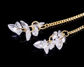 May include: A pair of gold dangle earrings with a chain and multiple clear crystal teardrop-shaped stones.