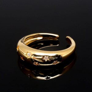 Peut inclure: Une bague en or avec une bande arrondie et de petites pierres claires serties en forme d'étoiles.