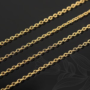 May include: A close-up of three gold chains, each with a delicate, oval-shaped link. The chains are arranged in parallel lines, creating a simple and elegant design.