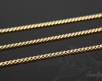 May include: A gold chain necklace with a curb link style. The chain is lying on a black surface.