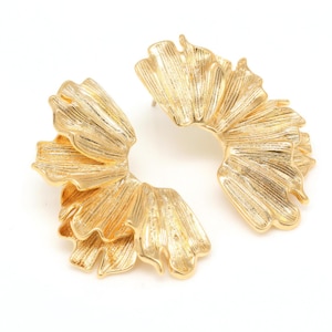 May include: A pair of large, gold-tone earrings with a unique, organic shape resembling flower petals. The earrings are made of metal and have a textured finish.