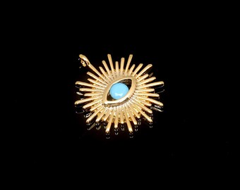 May include: Gold-toned pendant featuring a blue evil eye charm at its centre, surrounded by a sunburst design.