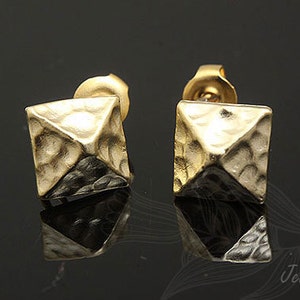 May include: A pair of gold-toned stud earrings with a pyramid-shaped design. The earrings have a textured surface.