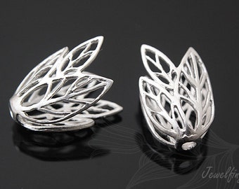 May include: Two silver-coloured, leaf-shaped jewellery components. Each component features an openwork design with intricate vein-like patterns. The components are displayed against a dark background, highlighting their metallic sheen. The components are likely used in jewellery making.