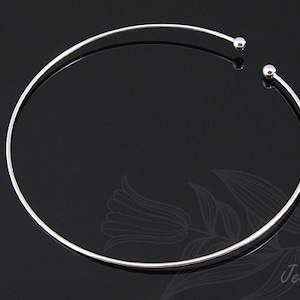 May include: A silver choker necklace with two small round balls at the ends.