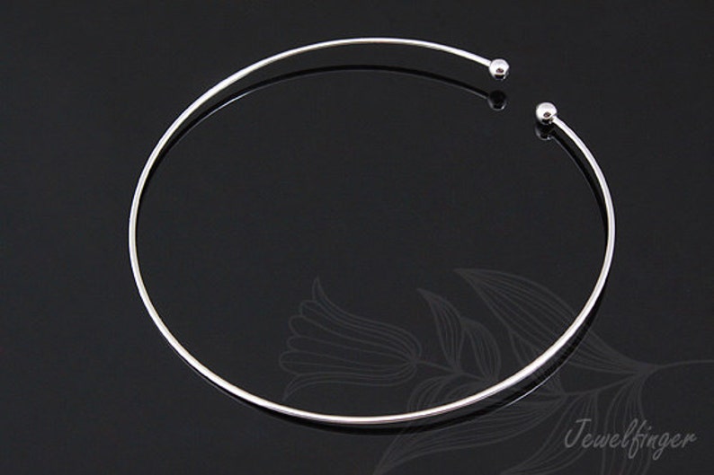 May include: A silver choker necklace with two small round balls at the ends.