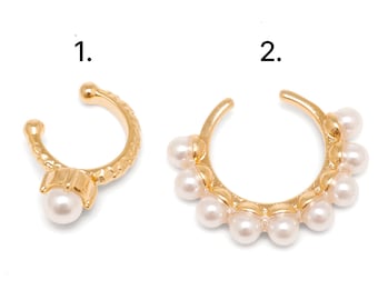 May include: Two gold-toned ear cuffs labeled 1 and 2. Ear cuff 1 features a single white pearl on a textured band. Ear cuff 2 is a larger circular band adorned with a row of eight white pearls along the outer edge of the gold-colored metal frame.