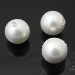 May include: Three white round beads with a hole in the center. The beads are smooth and have a pearlescent finish.