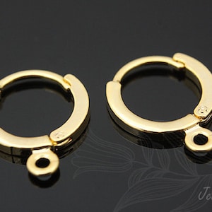 Puede incluir: Dos hallazgos de aro para pendientes de color dorado con un anillo de salto unido a la parte inferior de cada aro.