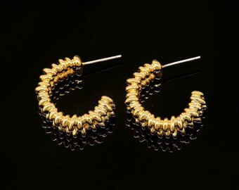 May include: A pair of gold hoop earrings with a textured, coiled design.