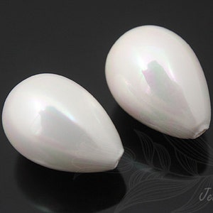 May include: Two pearlescent white teardrop-shaped beads. The beads have a smooth, glossy surface with subtle iridescent highlights. The beads are displayed against a dark background, emphasizing their shape and color.