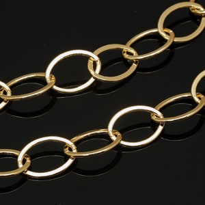 Puede incluir: Un collar de cadena de oro con eslabones ovalados. La cadena está sobre un fondo negro.