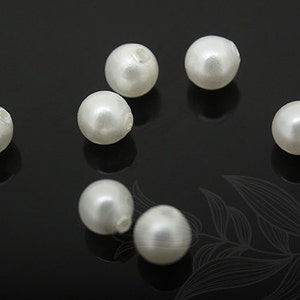 May include: A group of eight white pearl beads on a black background. The beads are round and smooth, and they have a slight shine.