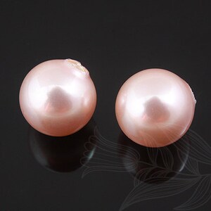May include: Two round, pale pink pearls on a black background.