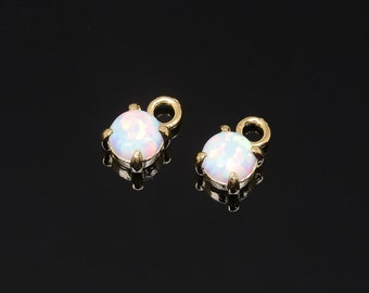 May include: Two gold-tone charms with a white opal stone and a loop for attaching to jewelry.