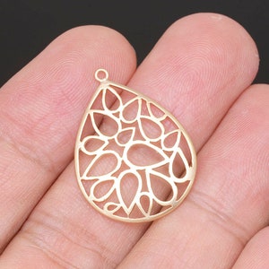 Puede incluir: Pendiente de metal dorado en forma de lágrima con un delicado y complejo diseño de formas de lágrima superpuestas.