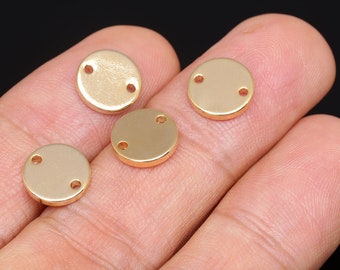 May include: Four gold-colored metal circles with two holes each. The circles are on a hand.