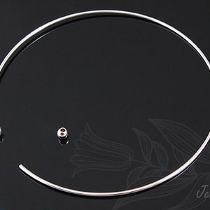 May include: A silver choker necklace with a simple, minimalist design. The necklace is made of a thin, flexible wire and has a small, round bead at each end.