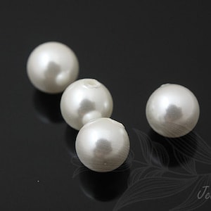 May include: Four white pearl beads on a black background.