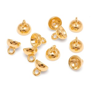 May include: A selection of gold-coloured jewellery findings, including bell-shaped beads with small loops and rounded beads with a loop on top. The beads are arranged on a white surface, showcasing their shiny, metallic finish. These findings are ideal for jewellery making.