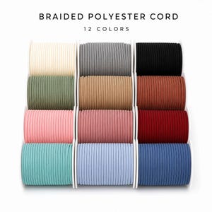 Puede incluir: Doce carretes de cordón de poliéster trenzado dispuestos en una cuadrícula. El texto BRAIDED POLYESTER CORD y 12 COLORS aparece en la parte superior. Los colores incluyen crema, gris, negro, verde oliva, beige, óxido, rosa claro, malva, rojo, cerceta, azul claro y azul marino.
