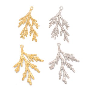 Peut inclure: Quatre pendentifs en métal en forme de branches, dorés et argentés. Chaque pendentif a une petite boucle en haut pour l'attacher à un bijou. Les branches ont un design texturé et détaillé, ressemblant à une brindille de feuillage.