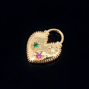 May include: Gold heart-shaped charm with a lock design. The charm has three gemstones: a pink, a green, and a white.