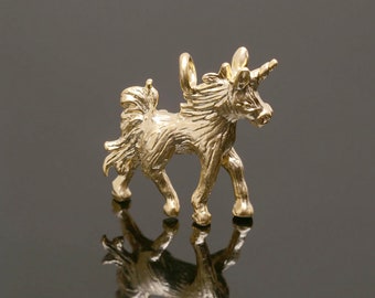May include: A gold-colored unicorn charm pendant. The unicorn is standing on all four legs with its head turned to the side. It has a long, flowing mane and tail.