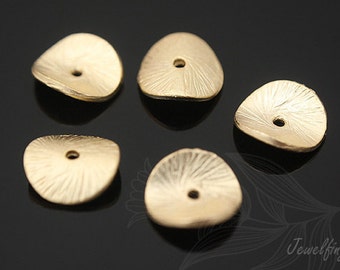 May include: Five gold-colored metal beads with a textured surface and a hole in the center. The beads are shaped like a rounded triangle.