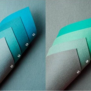 Op de afbeelding: Twee sets kleurstalen, elk uitgewaaierd om een reeks tinten weer te geven. De ene set loopt van lichtgrijs naar blauwgroen, met de nummers 57, 52, 53 en 51 zichtbaar. De andere set loopt van grijs naar groen, met de nummers 63, 68, 49 en 50 zichtbaar.