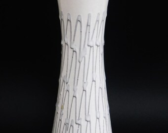 May include: A white ceramic vase with a gray geometric pattern. The vase has a narrow neck and a wide base.