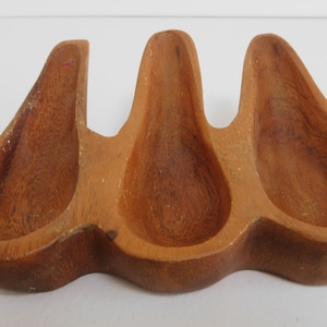 May include: Wooden pipe rack with three carved slots for holding pipes.