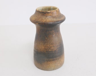 May include: A brown ceramic vase with a wide, rounded opening and a narrow base. The vase has a mottled brown and black glaze.